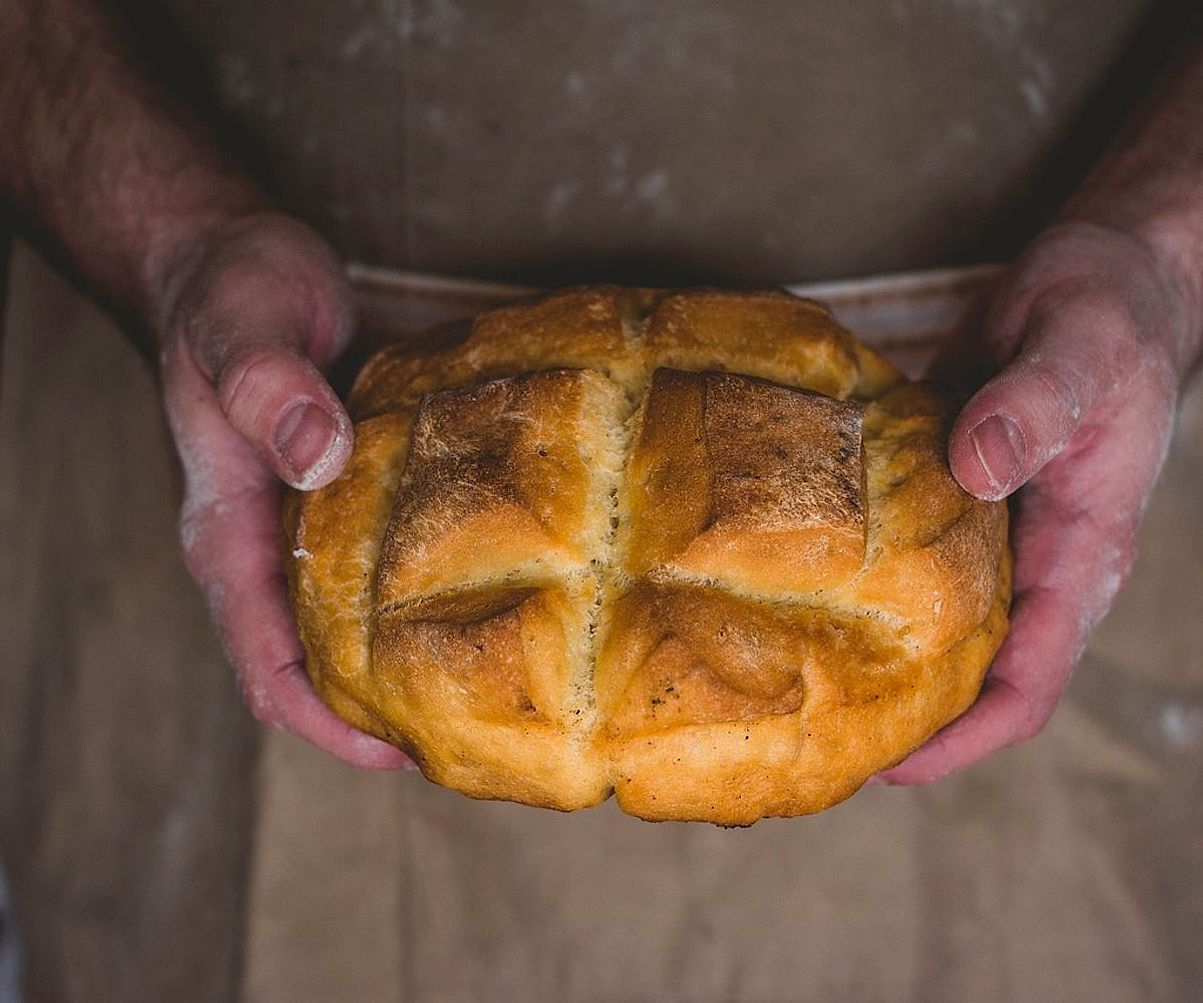 Hands shaping dough on a floured bench